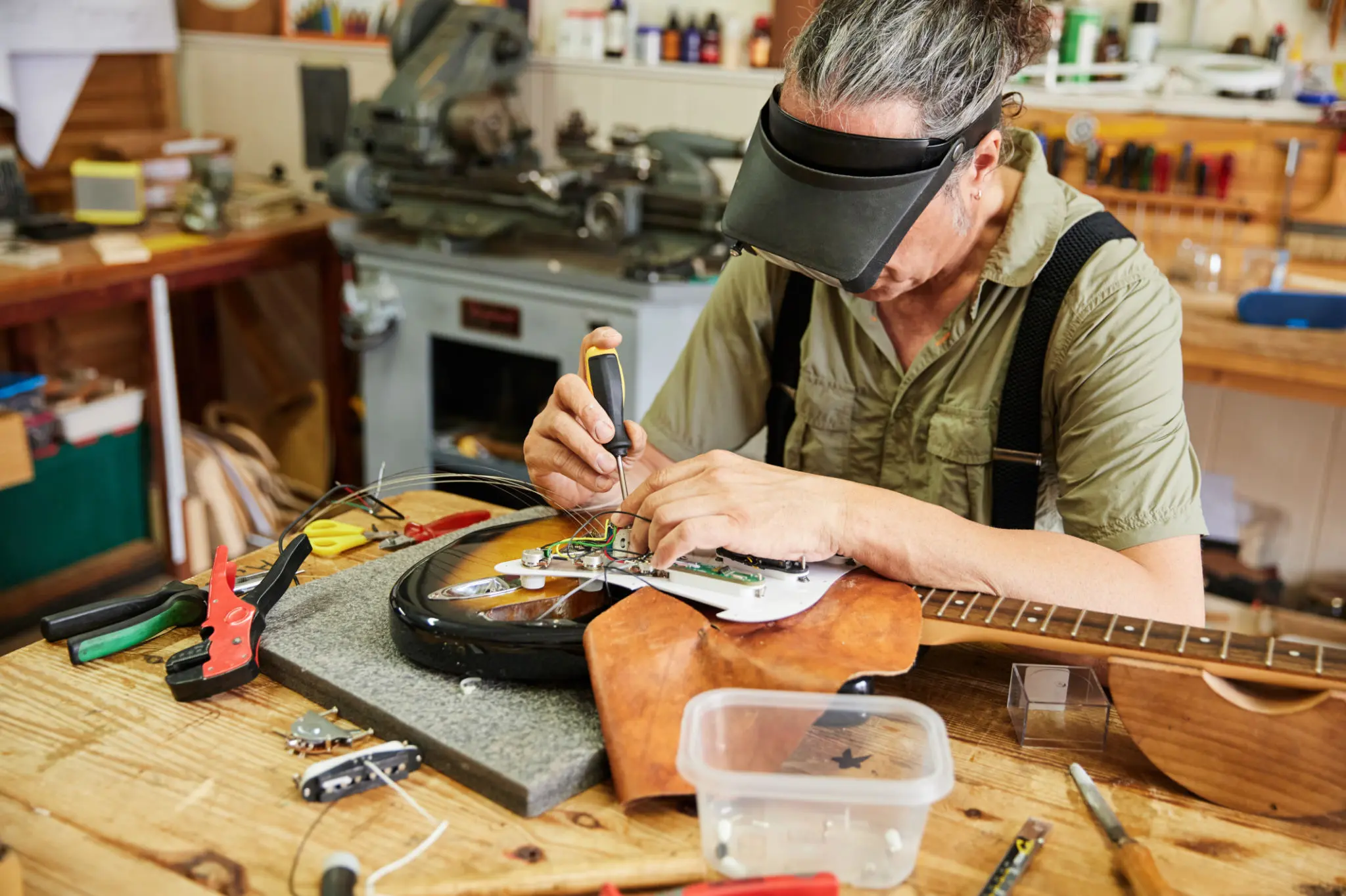 Person repairing electric guitar in workshop.