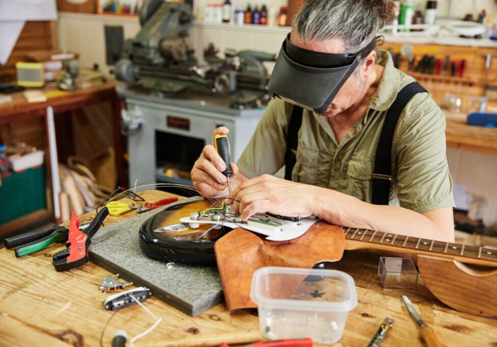 Person repairing electric guitar in workshop.